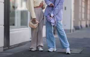 COLOGNE, GERMANY - MAY 01: Michi Brandl (L) seen wearing a pale yellow cropped pullover from Vival Studio, a gold necklace and gold earrings, a beige wide leg pants from Reserved, a beige Bottega Veneta bag and white sneakers from Nike and Justine Schlütter seen wearing a pale purple oversize blazer, a purple bra from Mango, a blue denim wide leg jeans, a purple Balenciaga Cargole Mini leather bag and white leather sneakers from Nubikk on May 01, 2022 in Cologne, Germany. (Photo by Jeremy Moeller/Getty Images)