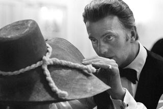 Portrait of designer Hubert de Givenchy (1927 - 2018) as he adjusts a hat of his own design, 20th century. (Photo by Jack Robinson/Hulton Archive/Getty Images)