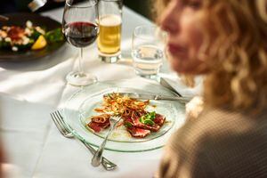 Woman sitting in restaurant with plate of freshly prepared food, close up