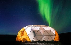 Carpa domo iluminada con aurora boreal en el fondo, en Narsaq Vestgronland, un lugar ubicado en Groenlandia