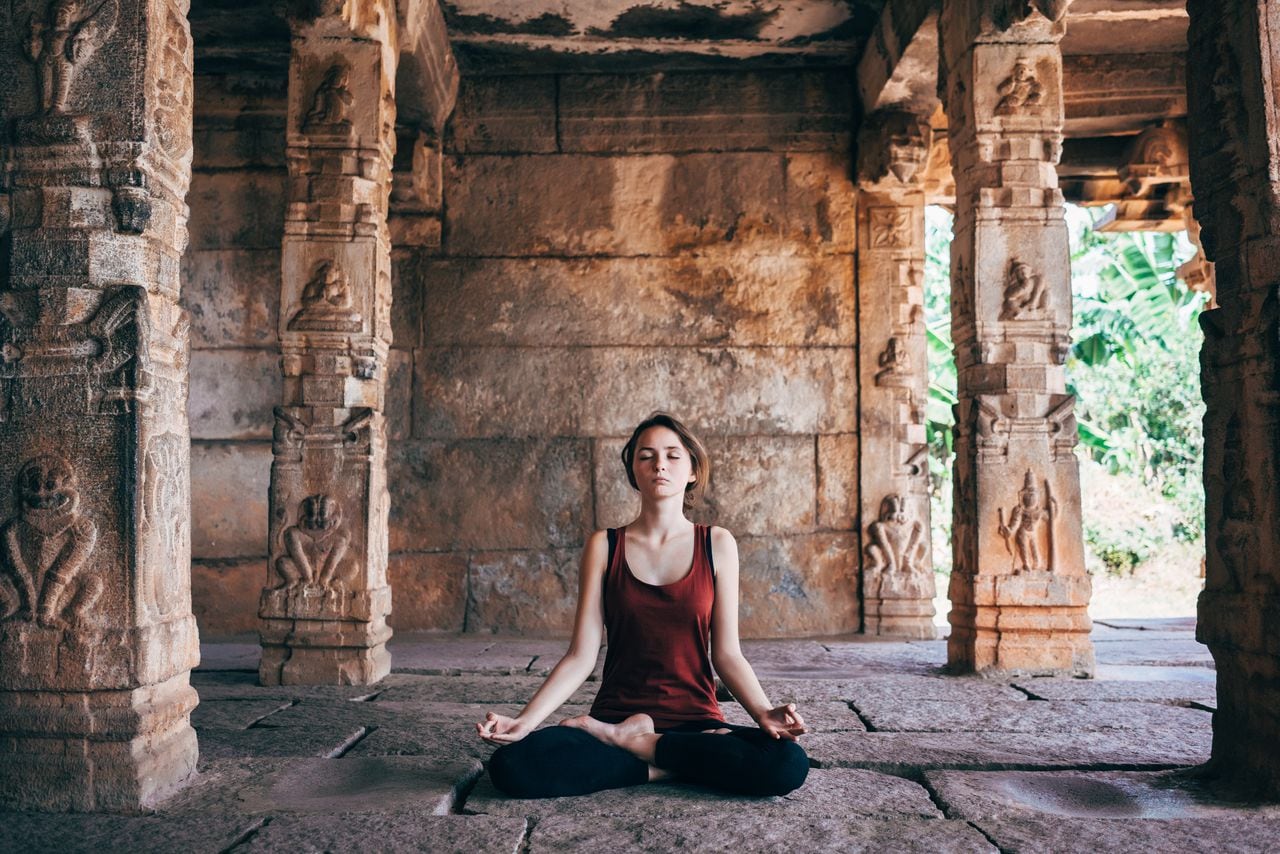 Mujer practicando yoga en un templo en India.