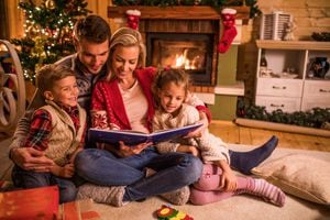 Young happy family reading fairy tales while relaxing at home during Christmas holidays.
