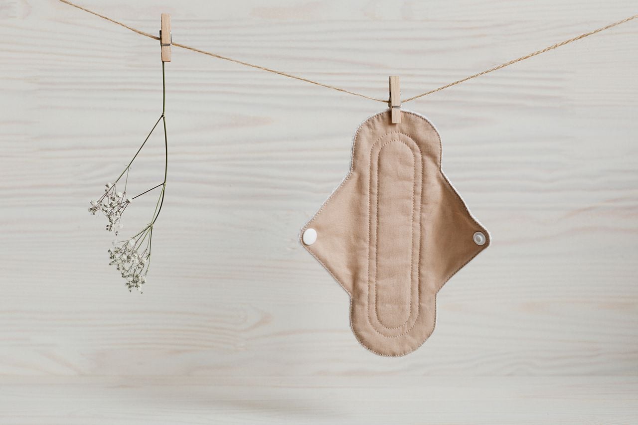 Eco-friendly reusable organic bio-cotton pad hanging on a rope on a wooden background with Gypsophila. Zero waste reusable washable cloth pad.