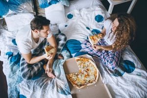 Una pareja comiendo pizza en una cama