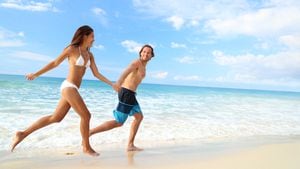 Feliz escapada de vacaciones en pareja en la playa. Jóvenes en bikini y traje de baño corriendo cogidos de la mano divirtiéndose en el paraíso de la playa tropical. Perfecta agua azul del océano y arena blanca.