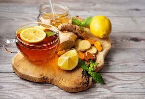 Taza de té de cúrcuma de jengibre sobre tabla de madera con ingredientes. Fondo rústico. Comida de invierno saludable