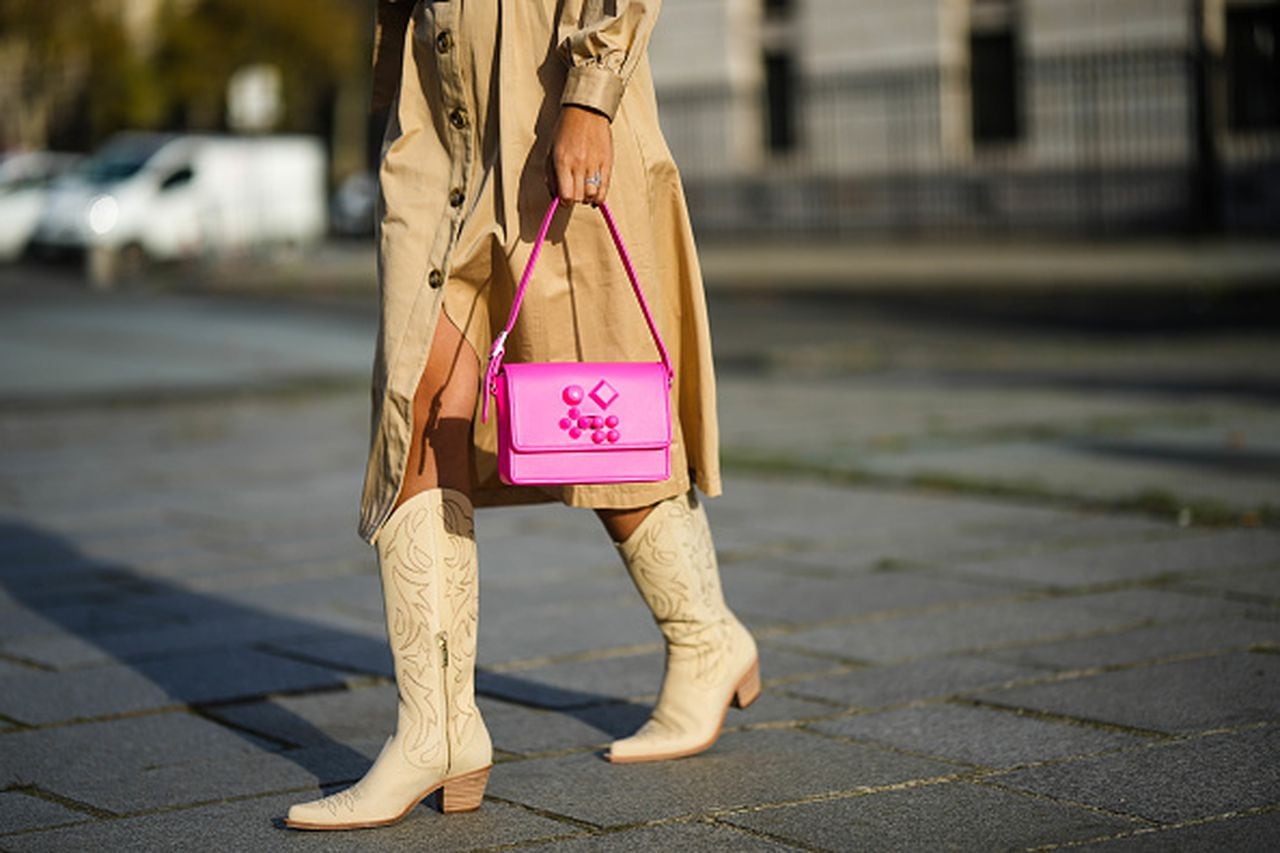 PARIS, FRANCE - NOVEMBER 02: Gabriella Berdugo wears a beige with embroidered ruffled shoulder / long puffy sleeves / belted / midi coat from Magali pascal, a neon pink shiny leather handbag from Louboutin, beige matte leather with embroidered pattern / block heels western boots from freelance, during a street style fashion photo session, on November 02, 2022 in Paris, France. (Photo by Edward Berthelot/Getty Images)