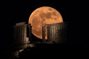 La superluna de flores se eleva detrás de las columnas del antiguo templo de mármol de Poseidón en el cabo Sunión, a unos 70 kilómetros (45 millas) al sur de Atenas, el miércoles 26 de mayo de 2021 (AP Photo / Petros Giannakouris).