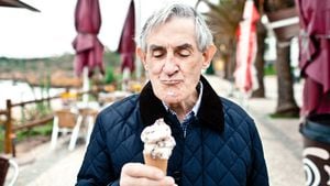 Elderly man eating an ice cream cone on a beach walkway during winter.