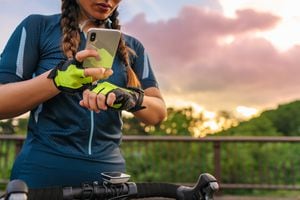 Una ciclista está configurando su reloj inteligente y su teléfono inteligente antes de andar en bicicleta