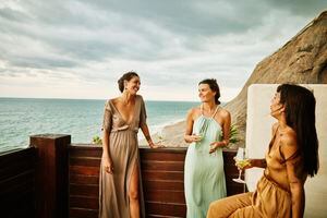 Medium wide shot of smiling and laughing female friends hanging out on deck of luxury hotel suite