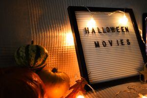 letter board on sofa with pumpkins and garland . Halloween movie .pumpkins ,close up , flat lay autumn decoration