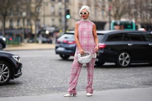 PARIS, FRANCE - JANUARY 23: Grece Ghanem wears white sunglasses, silver earrings from Chanel, a silver and pink embroidered rhinestones pattern turtleneck / sleeveless long t-shirt, matching silver and pink embroidered rhinestones pattern wide legs pants, a silver Serpenti watch from Bulgari, a gold Juste Un Clou ring from Cartier, a silver Messika ring, a silver shiny leather braided Jodie handbag from Bottega Veneta, white matte leather pointed / block heels ankle boots , outside Georges Hobeika, during  Paris Fashion Week - Haute Couture Spring Summer, on January 23, 2023 in Paris, France. (Photo by Edward Berthelot/Getty Images)