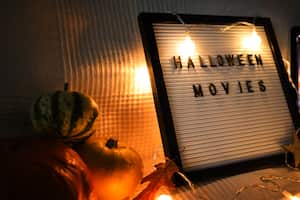 letter board on sofa with pumpkins and garland . Halloween movie .pumpkins ,close up , flat lay autumn decoration