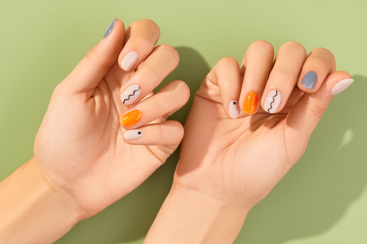 Close up womans hands with trendy minimal manicure on green background. Spring summer nail design. Beauty salon concept.