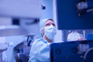 Anestesista controlando los parámetros gas y torrente sanguíneo del corazón externo en monitor durante la cirugía a corazón abierto.