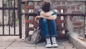 Niña llorando con la cabeza entre las manos sentada en el suelo