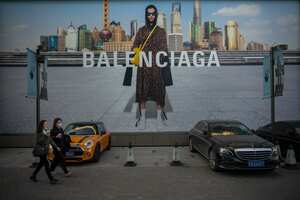 BEIJING, CHINA - OCTOBER 16: People walk in front of a Balenciaga ad on October 16, 2021 in Beijing, China. According to an action plan released on October 14, Beijing has unveiled a series of measures aimed at building the city into an international consumption center over the next five years. (Photo by Andrea Verdelli/Getty Images)