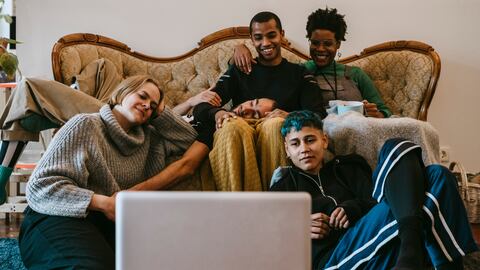 Smiling male and female watching movie on laptop in living room