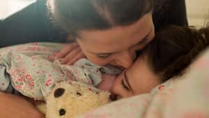 Affectionate mother with daughter in bed