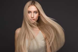 Beautiful blond girl in move with a perfectly smooth hair, and classic make-up. Beauty face. Picture taken in the studio.