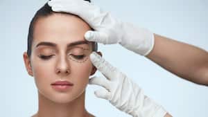 Tratamiento facial. Retrato de hermosa mujer sexy con ojos cerrados y líneas quirúrgicas negras en la piel. Primer De Las Manos Que Tocan La Cara Femenina Joven. Concepto de cirugía plástica. Alta resolución