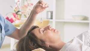 Alternative medicine therapist using pendulum to make a diagnosis