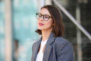 NEW YORK, NEW YORK - SEPTEMBER 14: A guest wears black sunglasses, a white cut-out / halter neck cropped top, a black and white checkered print pattern blazer jacket, outside Michael Kors, during New York Fashion Week, on September 14, 2022 in New York City. (Photo by Edward Berthelot/Getty Images)