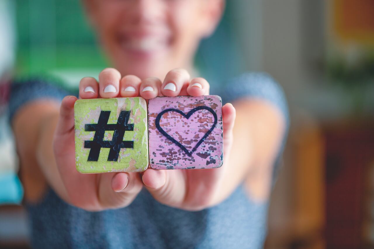 Mujer sosteniendo un signo de corazón de amor hashtag y sonriendo. Signo numeral, corazón