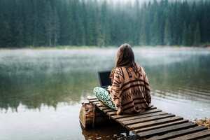 Woman Relaxing In Nature And Using Technology
