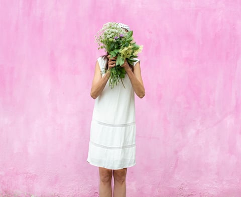 Woman in a white dress with a bouquet of flowers covering her face