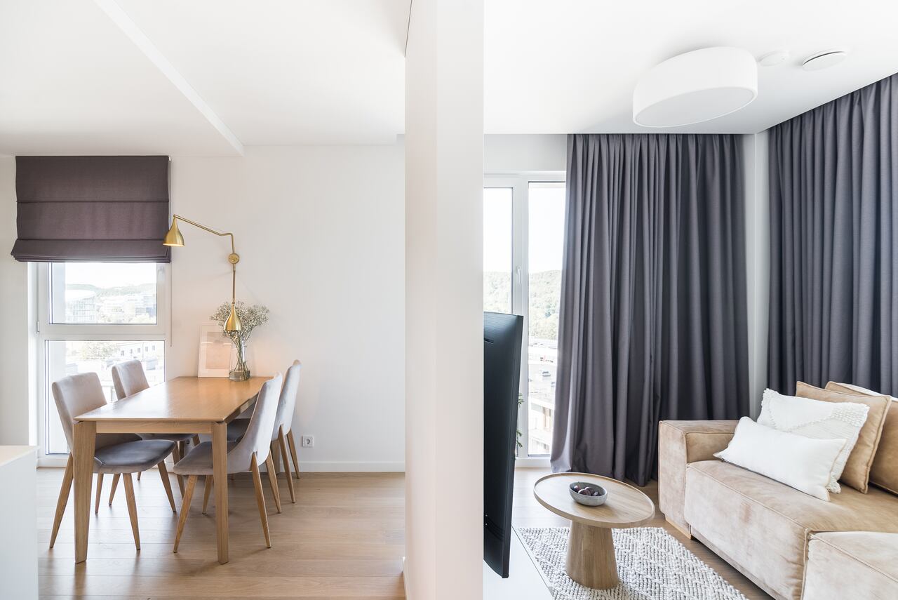 Apartamento nuevo y moderno con un comedor y salas de estar separados por la pared.