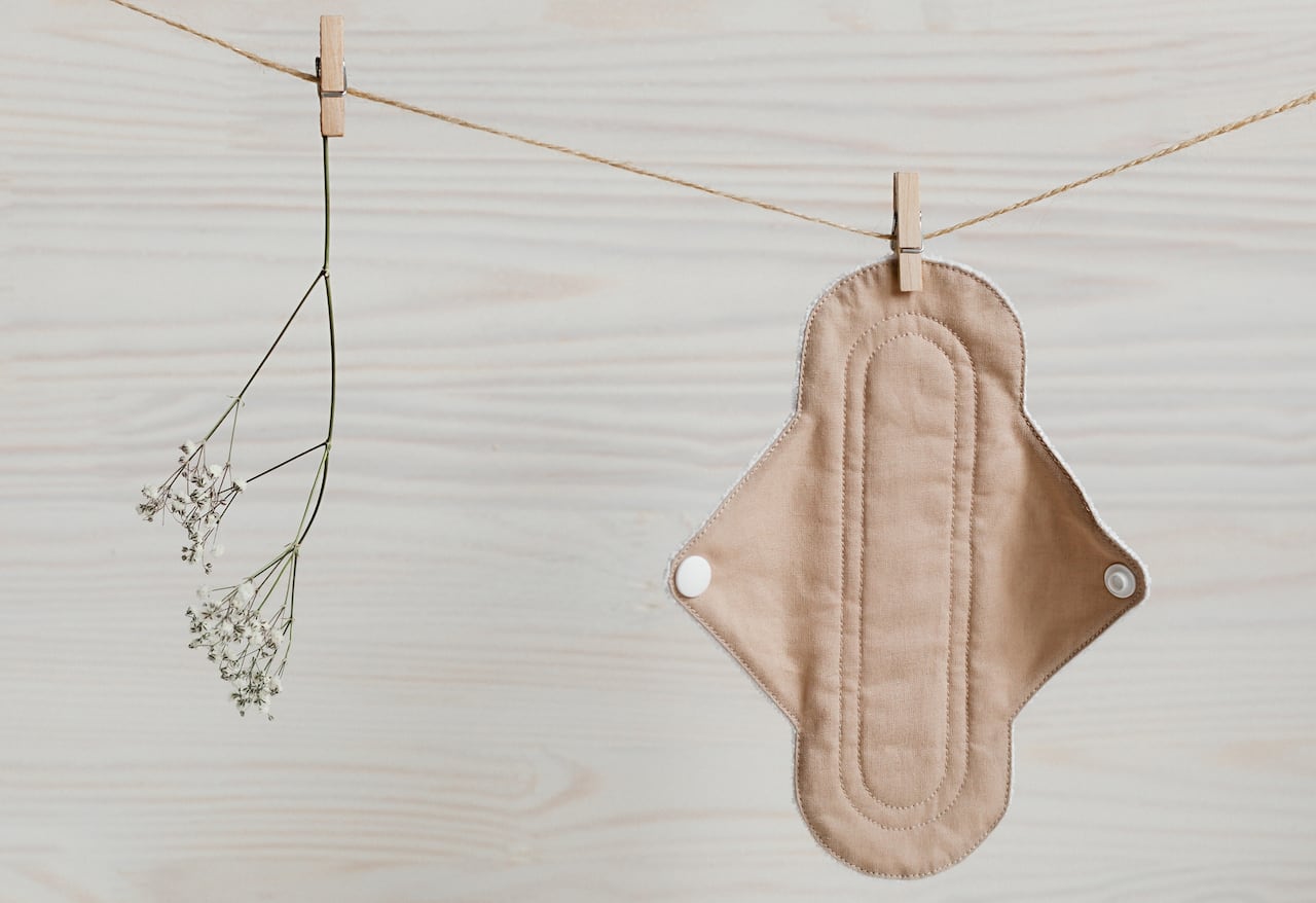 Eco-friendly reusable organic bio-cotton pad hanging on a rope on a wooden background with Gypsophila. Zero waste reusable washable cloth pad.