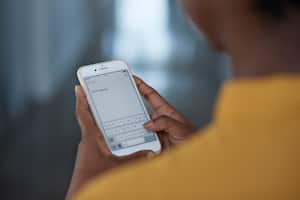 Persona enviando un mensaje desde su celular.