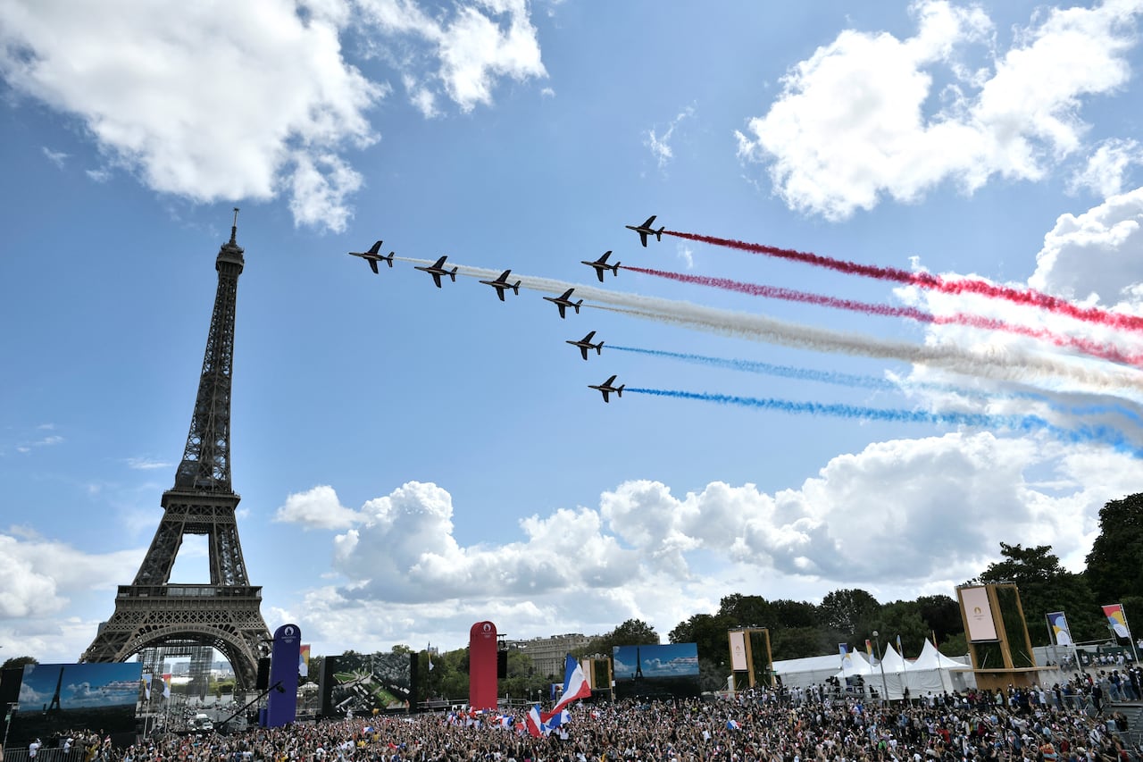 La patrulla aérea francesa 'Patrouille de France' sobrevuela la aldea de fans de El Trocadero frente a la Torre Eiffel, en París, el 8 de agosto de 2021 tras la transmisión de la ceremonia de clausura de los Juegos Olímpicos de Tokio 2020. (Foto de STEPHANE DE SAKUTIN / AFP)
