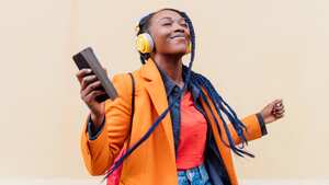 Italy, Milan, Woman with headphones and smart phone dancing outdoors