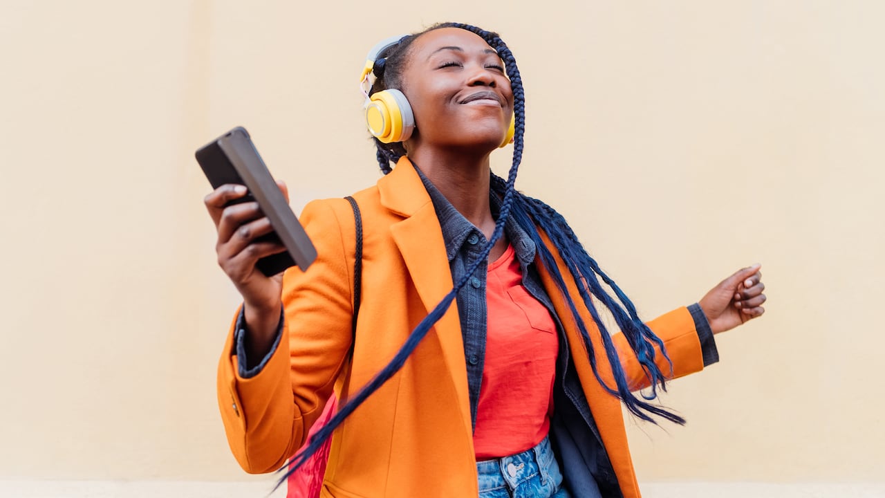 Woman with headphones and smart phone dancing outdoors