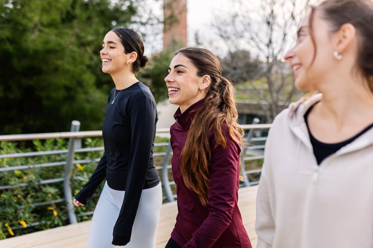 Three athletic young women enjoying a walk together outdoors, promoting a healthy and active lifestyle at city park. Female friendship concept.