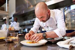 Head chef finishing dish in kitchen at restaurant