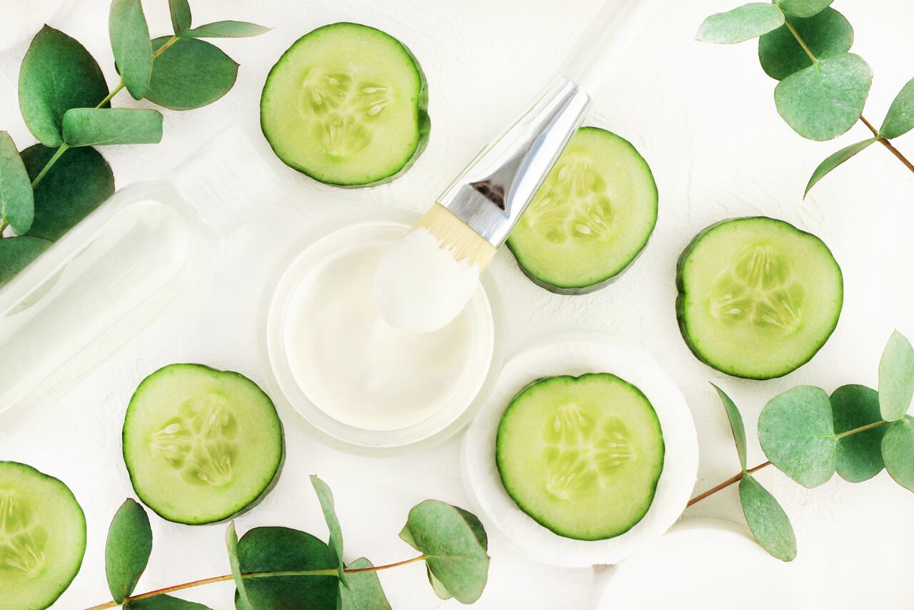 Tarro de fabricación de mascarilla facial hidratante refrescante, cepillo, hojas de eucalipto. Rodajas de pepino verde fresco cosmético cuidado de la piel botánico.