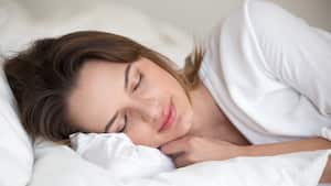 Mujer joven con cara hermosa durmiendo bien en sábanas de algodón blanco y almohada suave durmiendo en una cama cómoda y acogedora en casa o en el hotel disfrutando de una siesta saludable descansando lo suficiente para una buena relajación