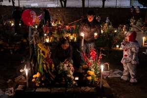 Familiares pasan la noche junto a la tumba de sus seres queridos en el cementerio San Gregorio Atlapulco durante las festividades del Día de Muertos en las afueras de la Ciudad de México, el martes 1 de noviembre de 2022.
