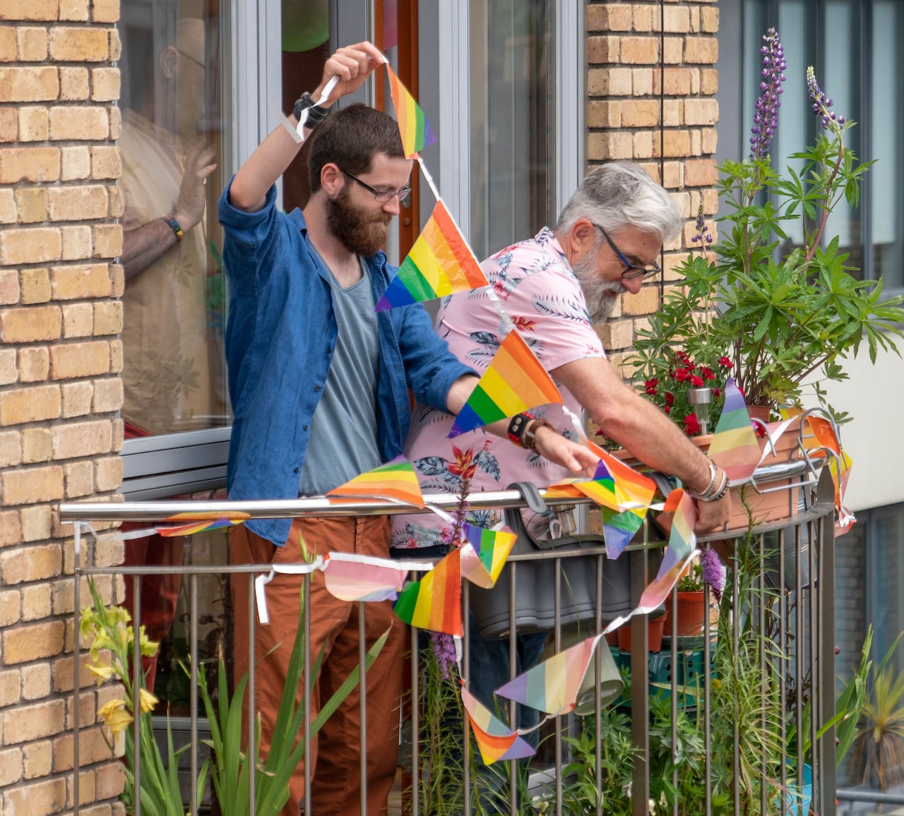 Friends decorating and preparing a balcony in support of LGBTQI+ Pride Parade from home.