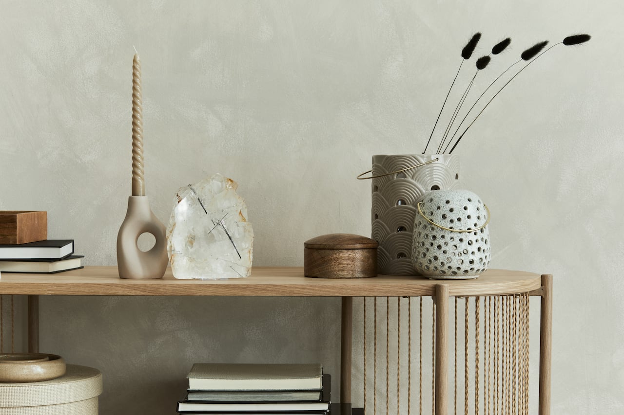 Stylish living room interior design with console. Sculpture, candlectick, minerals and personal accessories. Copy space. Template.