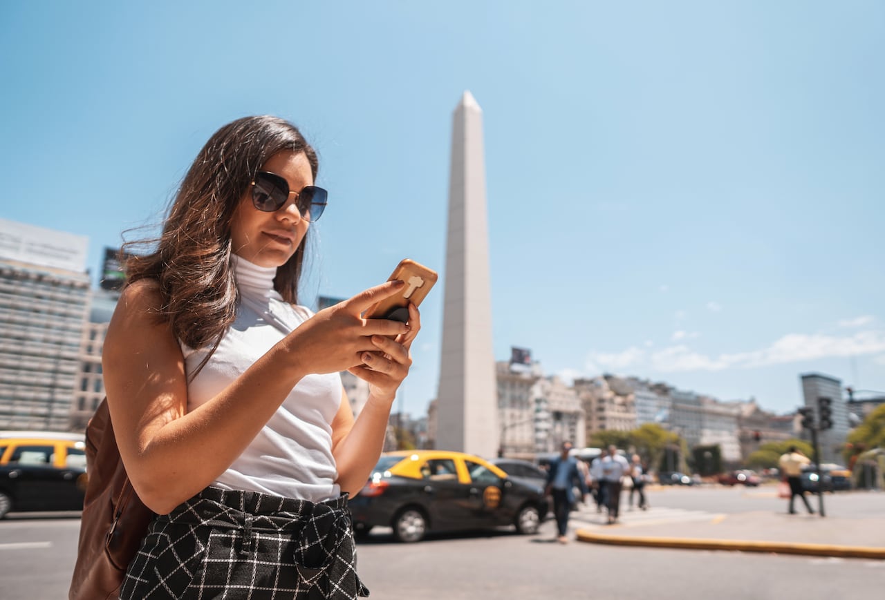 Tourist crossing the crosswalk and using phone on the streets of Caba in Buenos Aires, Argentina