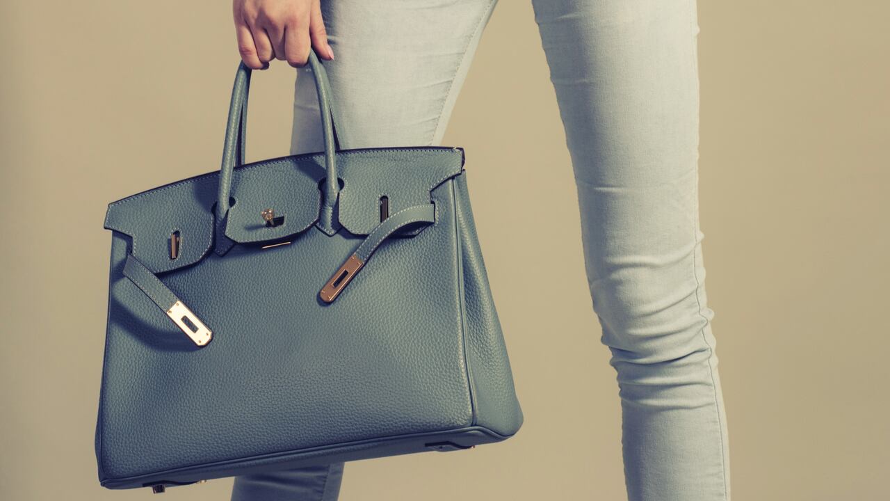 Close up woman with stylish leather big bag in hand on gray background