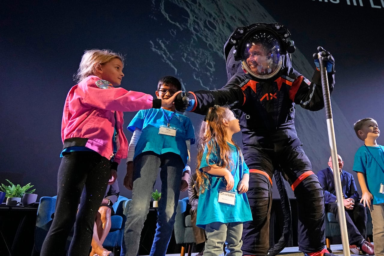 CORRECTS ID AT RIGHT TO RUSSELL RALSTON, NOT MARK GREELEY - Axiom Space chief engineer Jim Stein, left, bumps fists with deputy manager for extravehicular activity Russell Ralston while demonstrating a prototype spacesuit, Wednesday, March 15, 2023, in Houston. NASA selected Axiom Space to design the spacesuits that its moonwalking astronauts will wear when they step onto the lunar surface later this decade. (AP Photo/David J. Phillip)