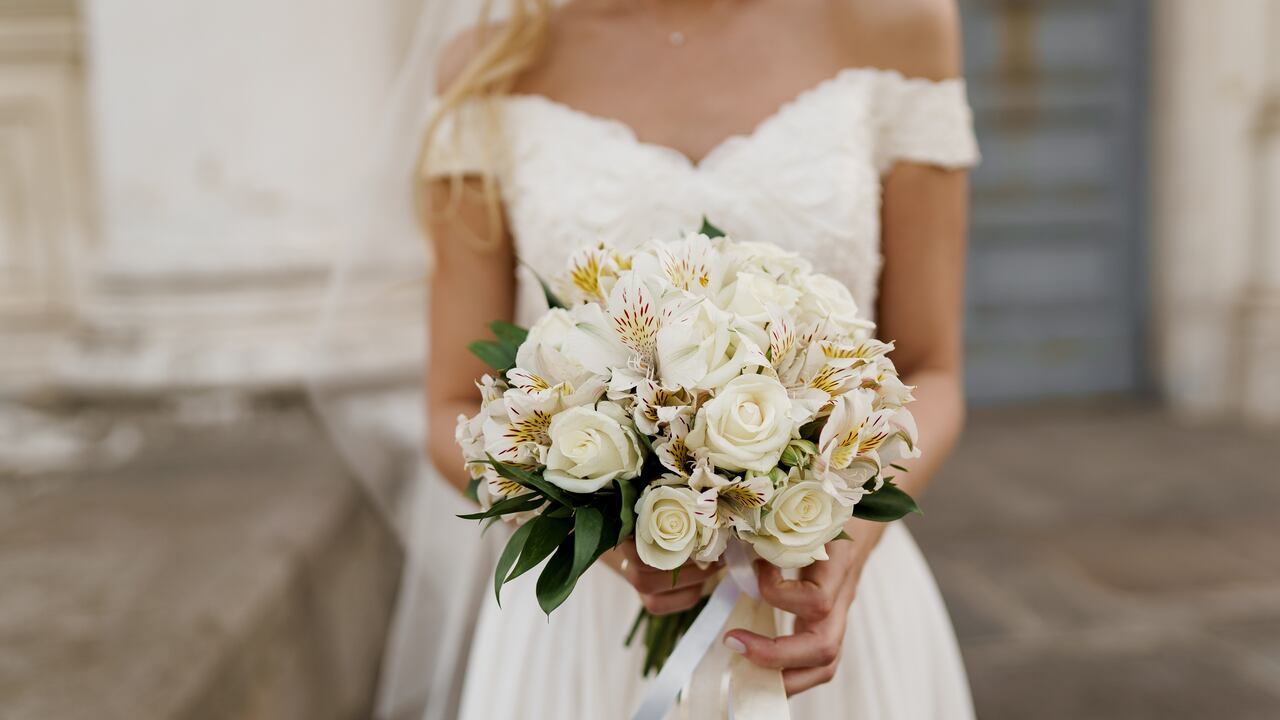 Bride in dress holds bouquet.