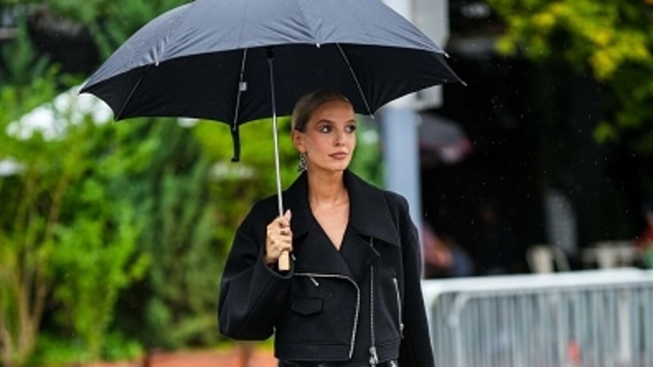 NEW YORK, NEW YORK - SEPTEMBER 11: Leonie Hanne wears a black umbrella, a silver and black Triangle pendant earrings from Prada, a black felt / zipper / oversized cropped jacket, a black shiny varnished leather short skirt, gold rings, black shiny leather strappy heels sandals , outside Khaite, during New York Fashion Week, on September 11, 2022 in New York City. (Photo by Edward Berthelot/Getty Images)