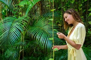 28-year-old Latin woman with blond hair and long yellow dress is enjoying the nature of her new summer home in Cartagena